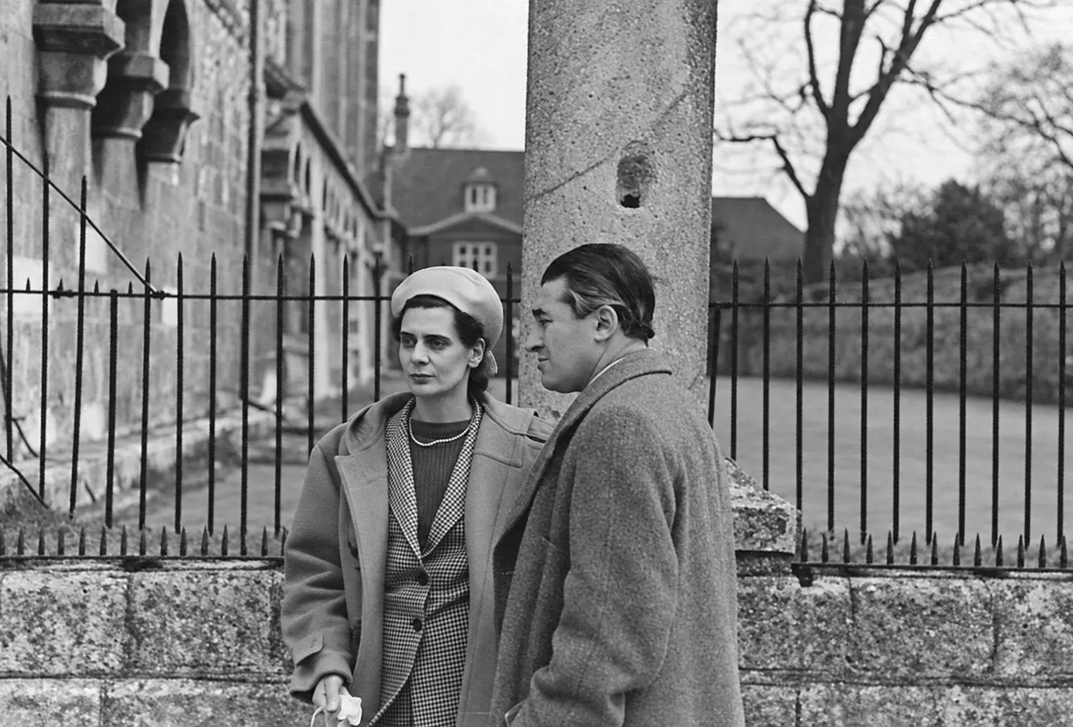 Otto und Jeanne Pächt in Mänteln vor einem Eisenzaun und einem Steingebäude